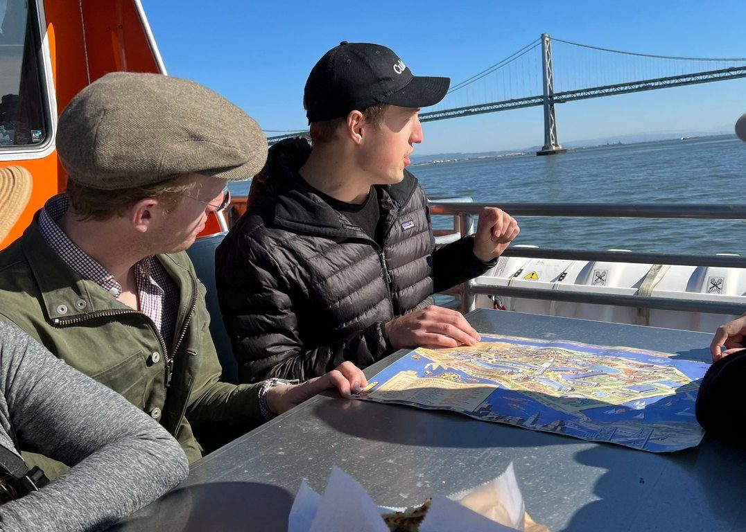 Guests on a ferry with the Bay Bridge behind them