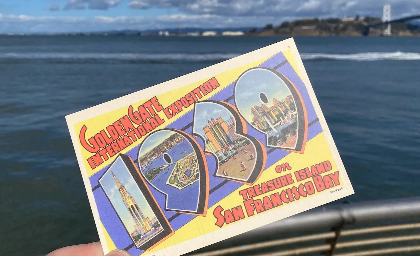 A postcard from the 1939 Golden Gate International Exposition on Treasure Island, held up across the water from the island and the Bay Bridge
